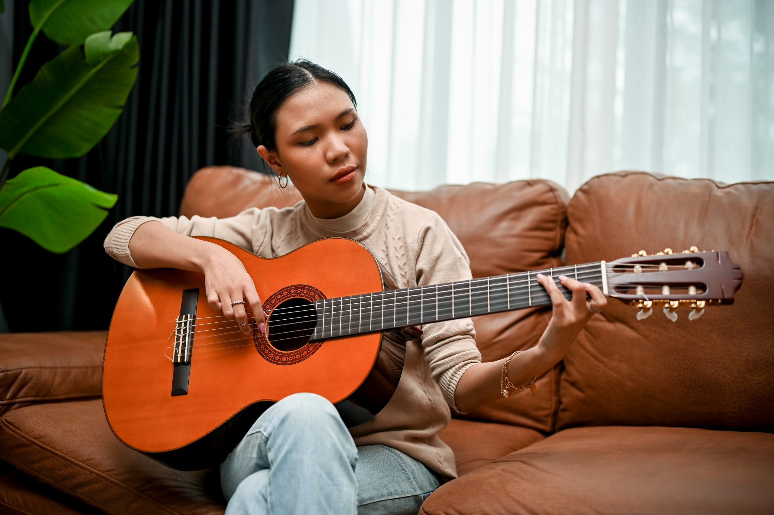 woman sitting on the couch and playing the guitar