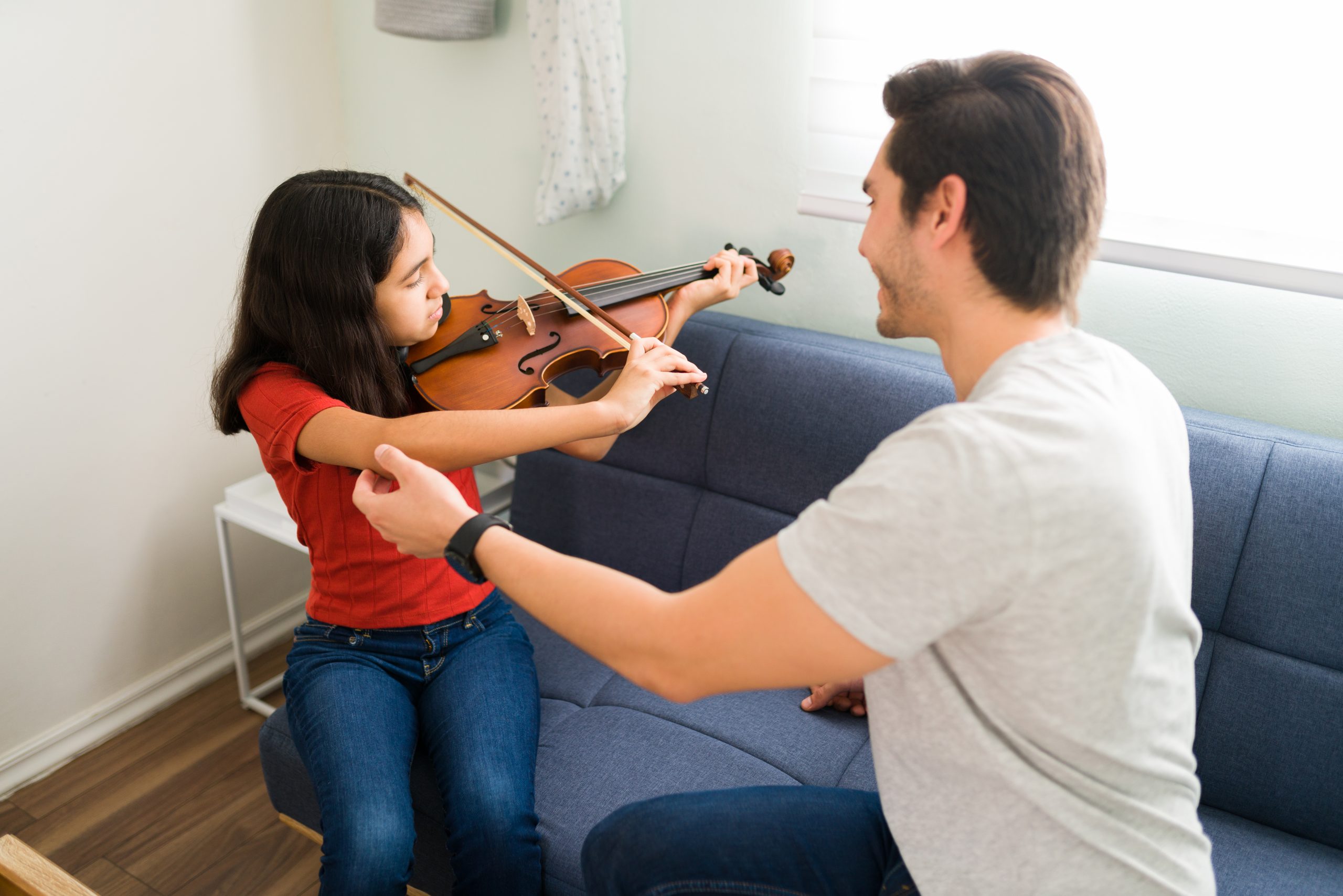 violin teacher correcting the posture of a student learning the violin