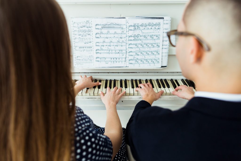 A young beginner adult couple playing music on a piano.